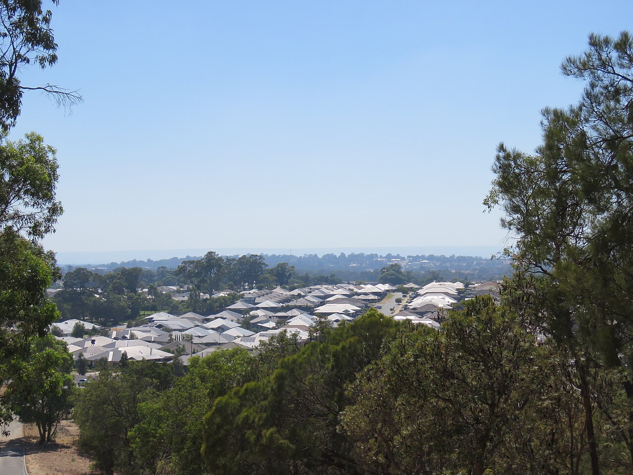 Baldivis, WA — Residential rooftops surrounded by trees under clear sky
