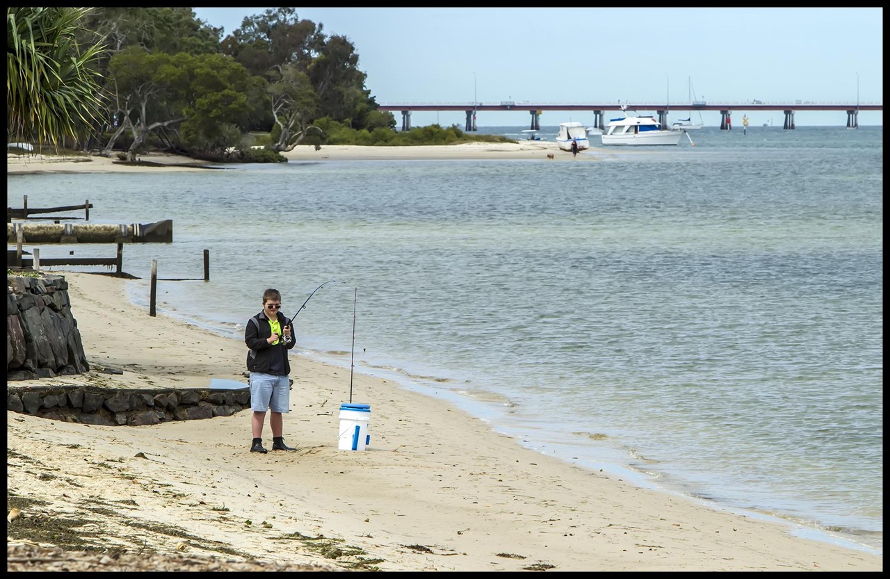 Banksia Beach, QLD, Fisherman on sandy beach near a bridge
