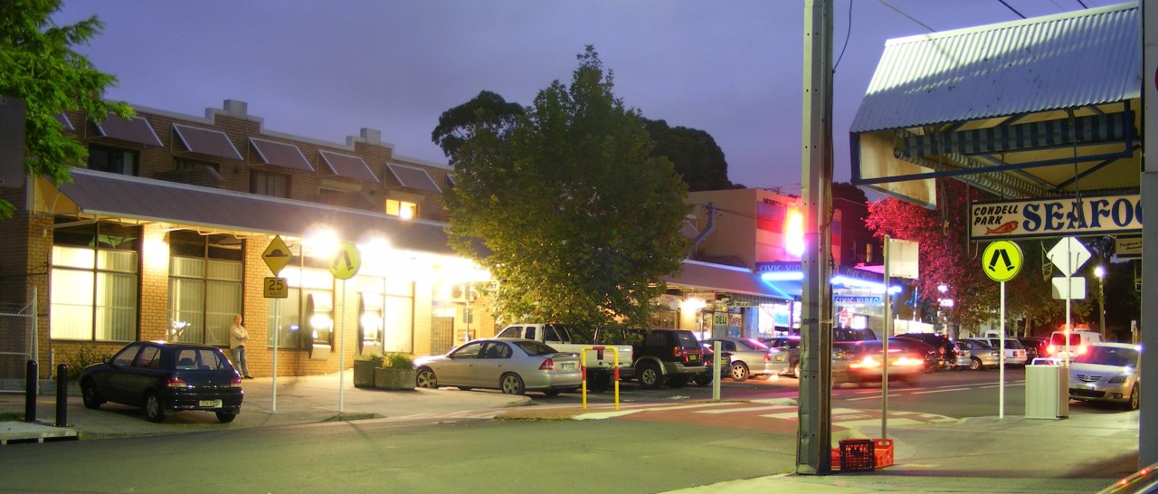 Condell Park, NSW, Street scene with cars and shopfronts at dusk