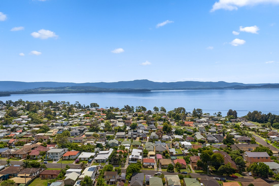 Oak Flats, NSW, Suburban homes near a large lake under blue sky
