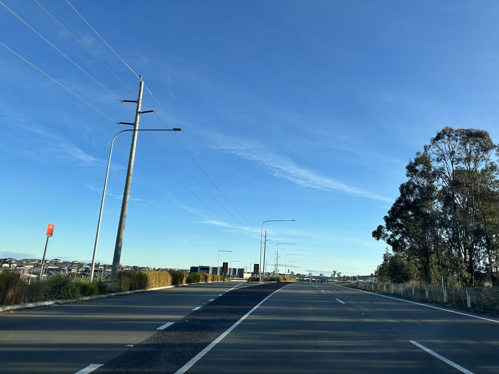 Oran Park, NSW, Wide road with power lines and trees