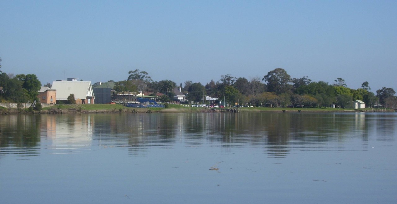 Raymond Terrace, NSW, Reflections on a riverbank with distant buildings