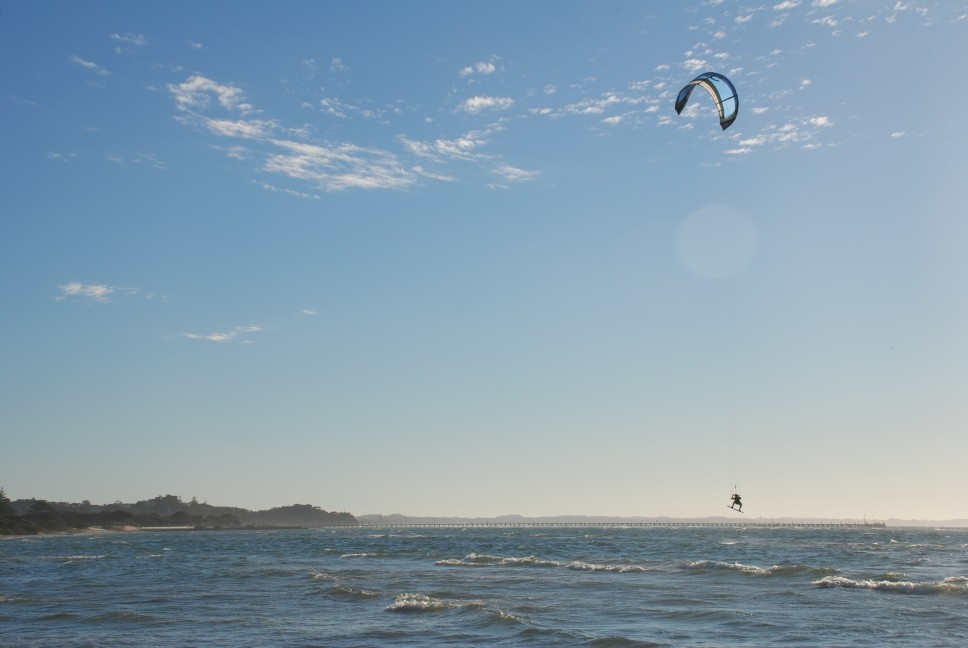 Rye, VIC, Kite surfer over ocean waves near shoreline