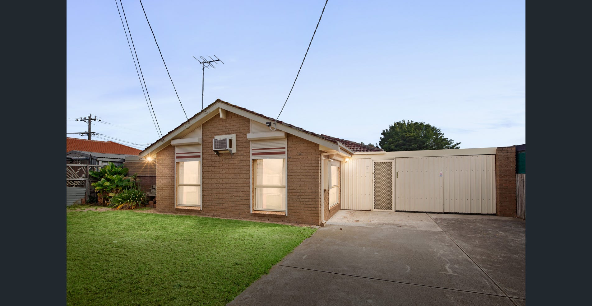 An established detached brick home with a tiled roof, front lawn and a driveway beside the house.